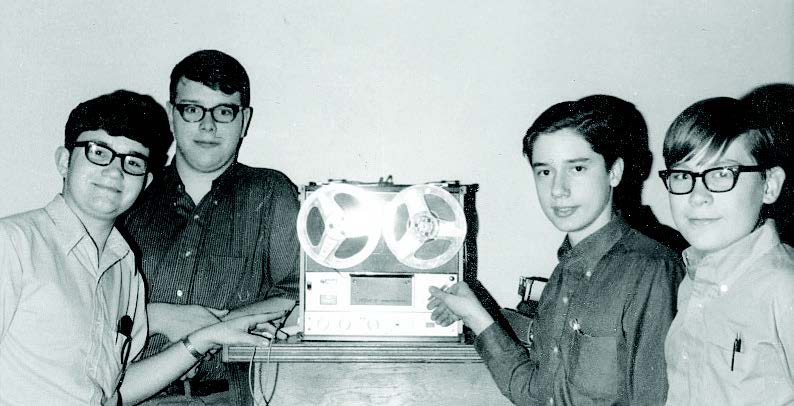 black and white image of old video equipment with 4 people around it