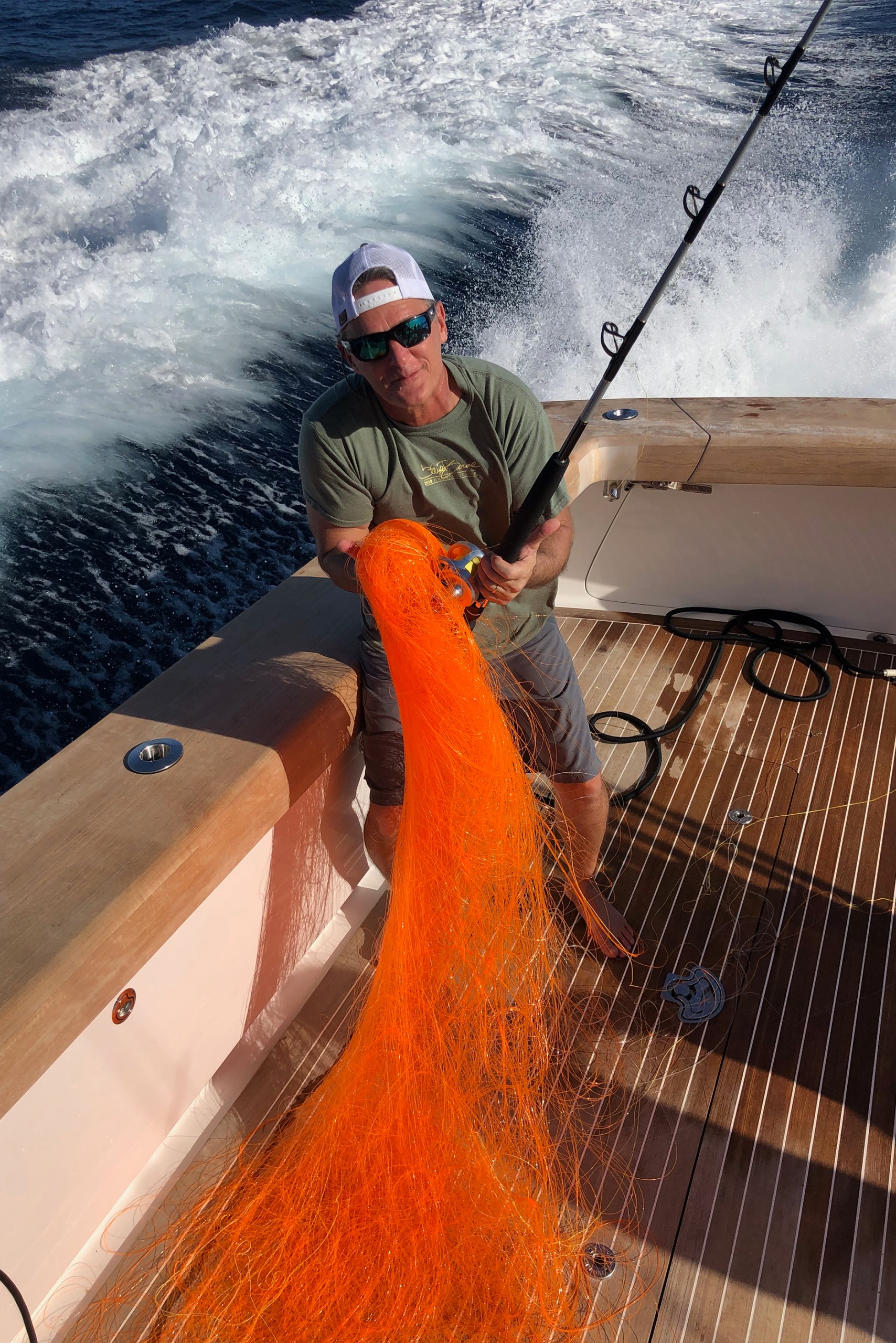 a guy holding a bunch of fishing line as a joke on back of boat