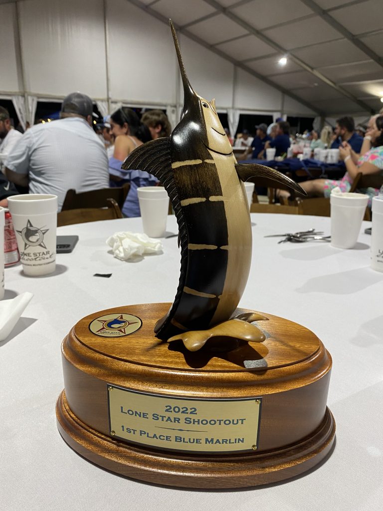 The 1st Place Blue Marlin trophy resting on a table.